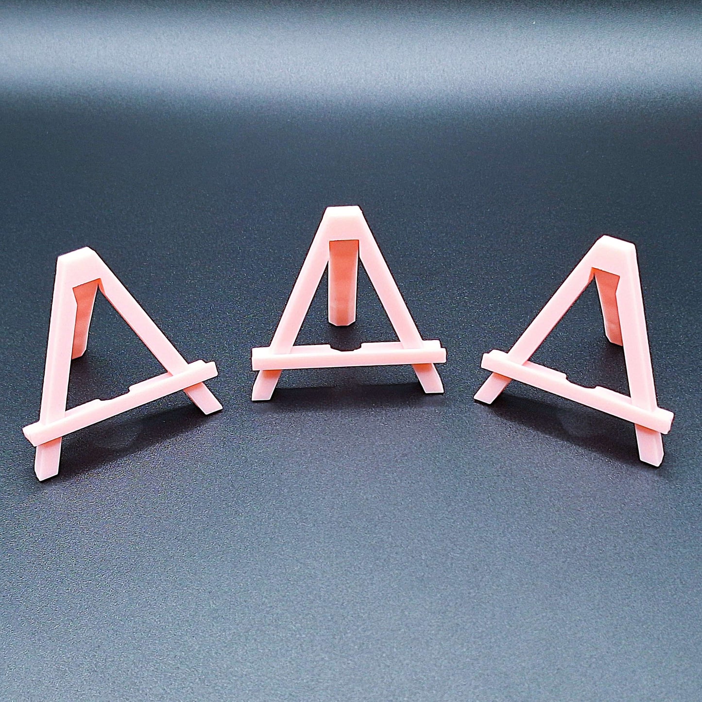 Mini foldable easels in pink – sleek and portable display stands ideal for showcasing coins, trading cards, artwork, signs, photos, or merchandise at craft fairs, shops, and events.