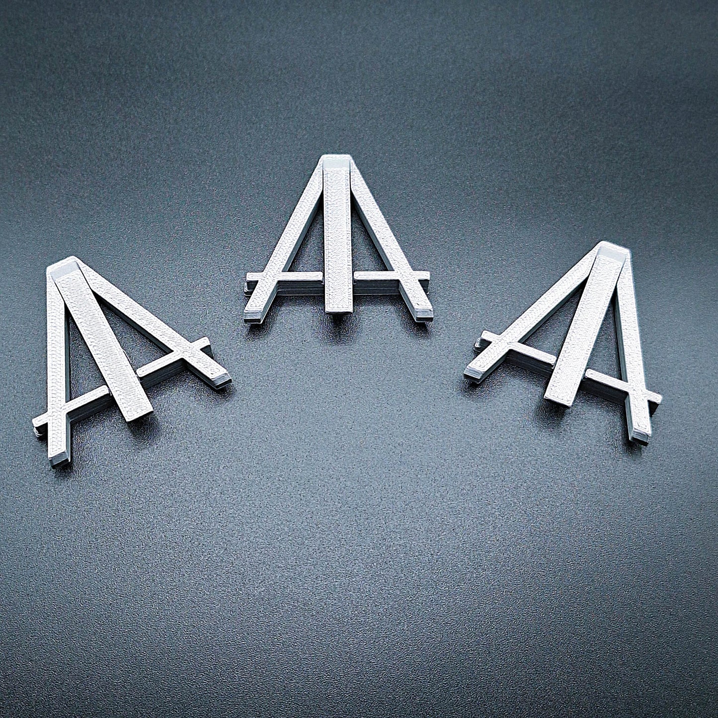 Mini foldable easels in silver – sleek and portable display stands ideal for showcasing coins, trading cards, artwork, signs, photos, or merchandise at craft fairs, shops, and events.