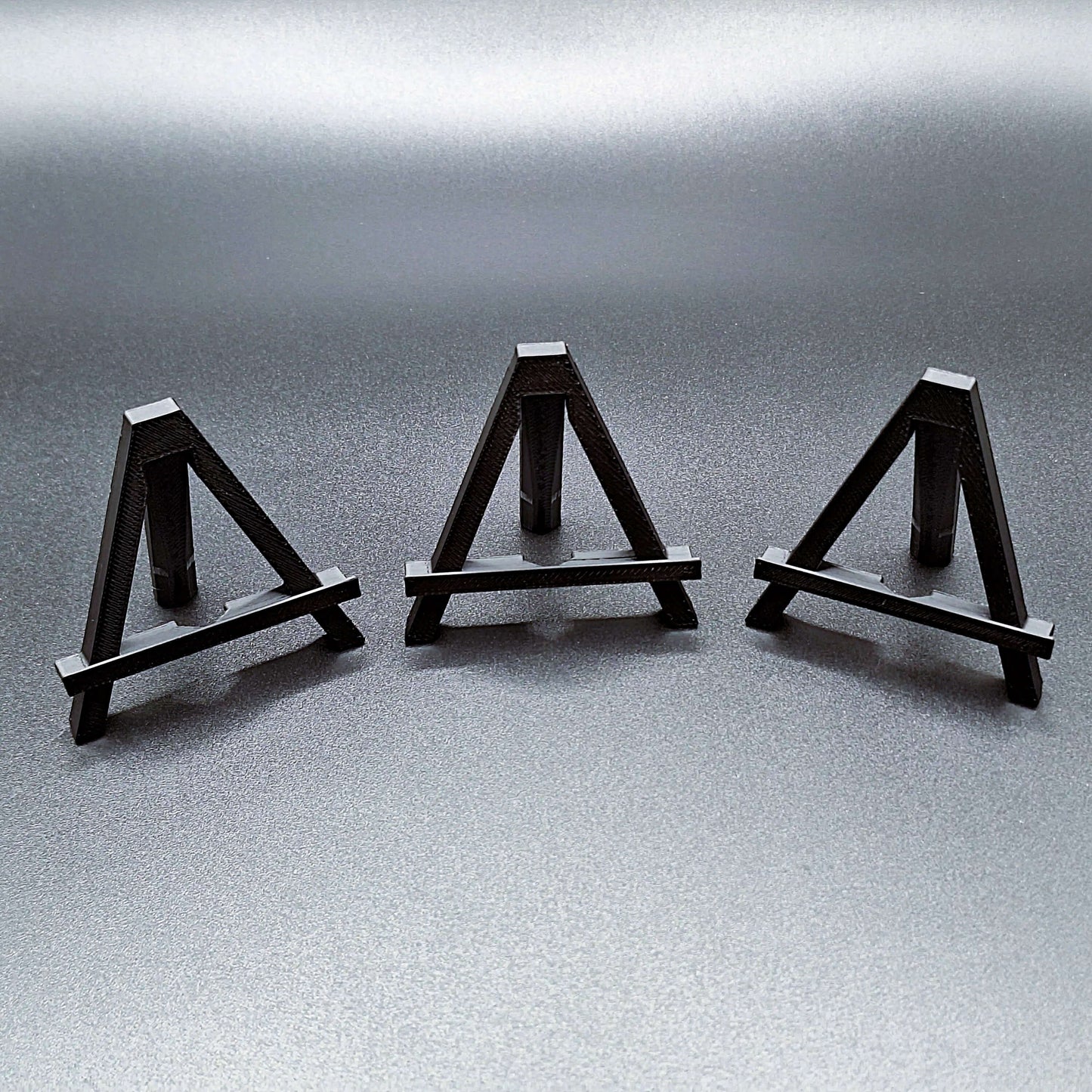 Mini foldable easels in black – compact and portable display stands, perfect for showcasing coins, trading cards, art, photos, or products at craft fairs, markets, and retail displays.
