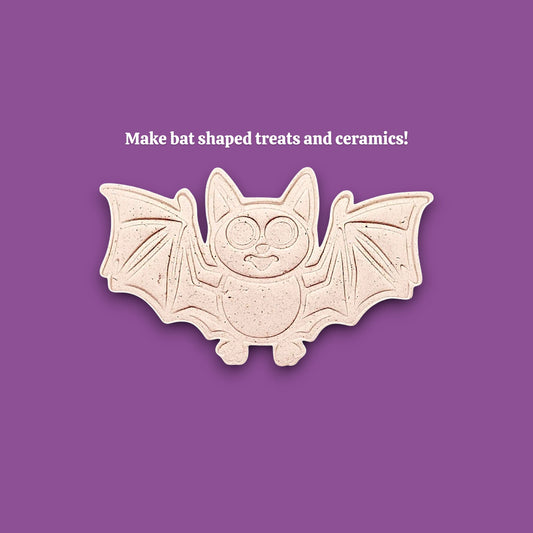 Dough cutout with bat design pressed by cutter and stamp set, showing detailed lines, great for easy Halloween cookie decorating without icing.