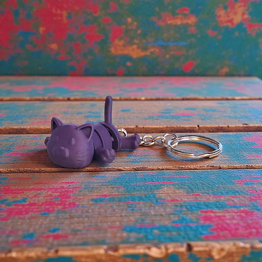 Handmade and customizable articulated cat keychain in purple, great for keys, backpacks, and small gifts with charm.