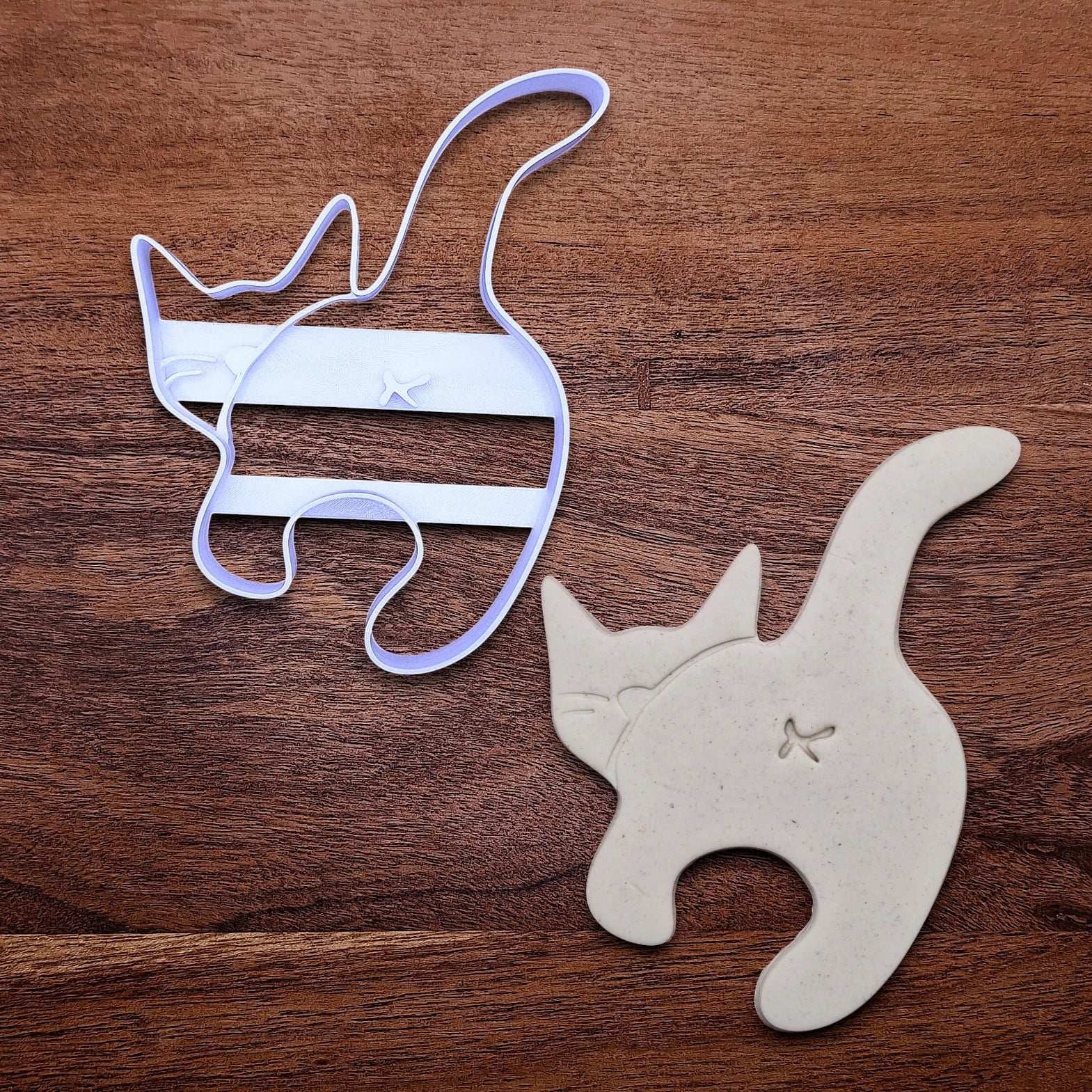 Handmade and customizable cat butt cookie cutter stamp combo alongside a dough cutout and imprint, perfect for gifting, gag gifts, white elephant gifting, and cat themed parties and treats.