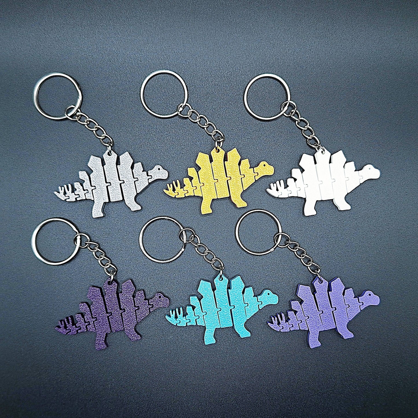 Top view of six fidget dinosaur keychains with articulated segments, ideal for sensory use, kids’ gifts, or dino-themed party favors.