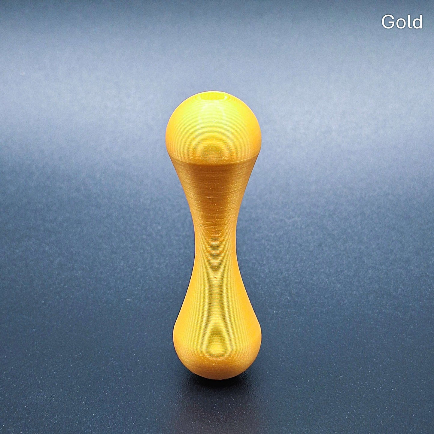 Gold knucklebone fidget toy with sleek finish, handmade from biodegradable PLA plastic for smooth flips, rolls, and sensory focus.