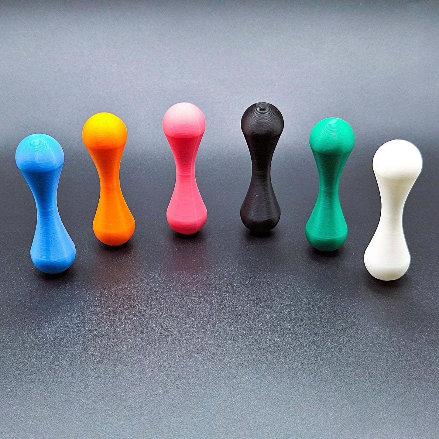 Six colorful knucklebone skill toys lined up, showcasing their vibrant eco-friendly design and ideal size for tactile focus and fidget play.