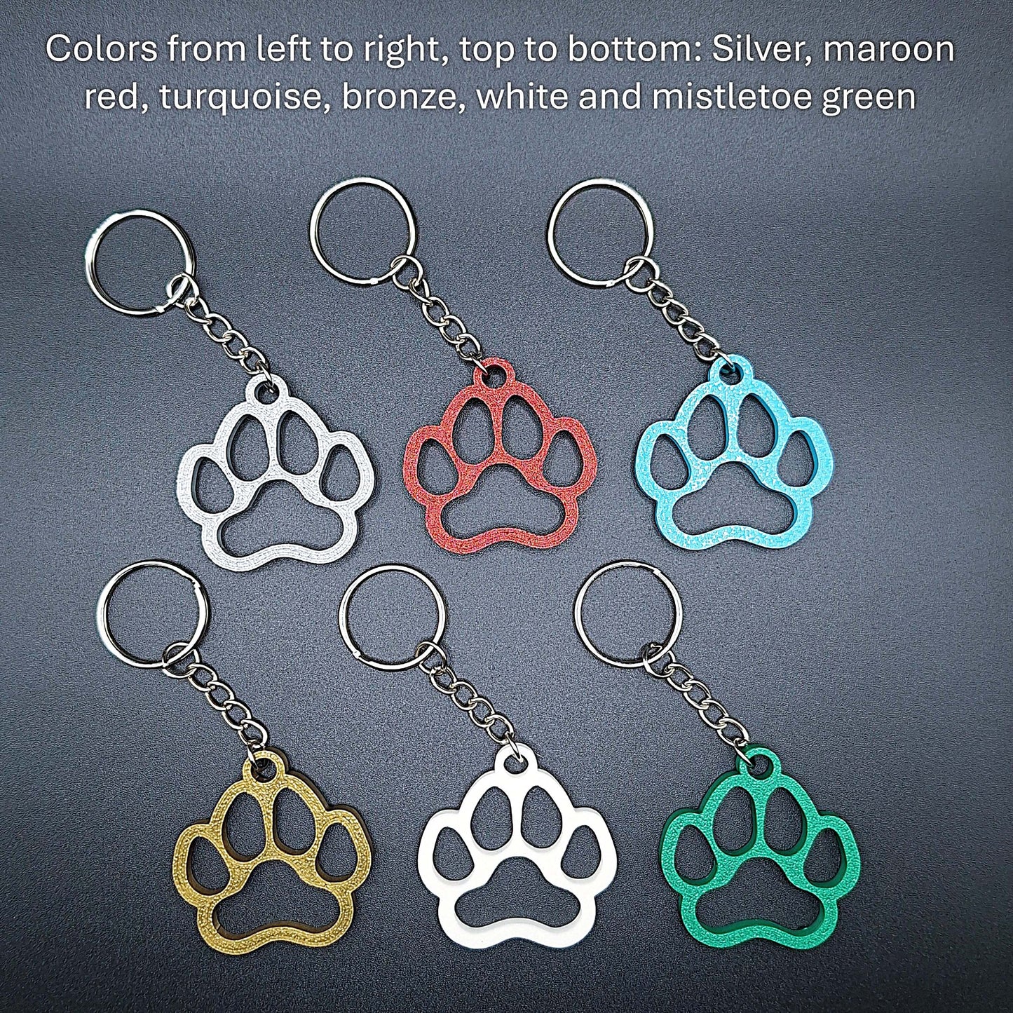 Six paw print keychains in assorted colors, made from biodegradable PLA plastic, perfect for dog moms, cat lovers, or rescue volunteers.