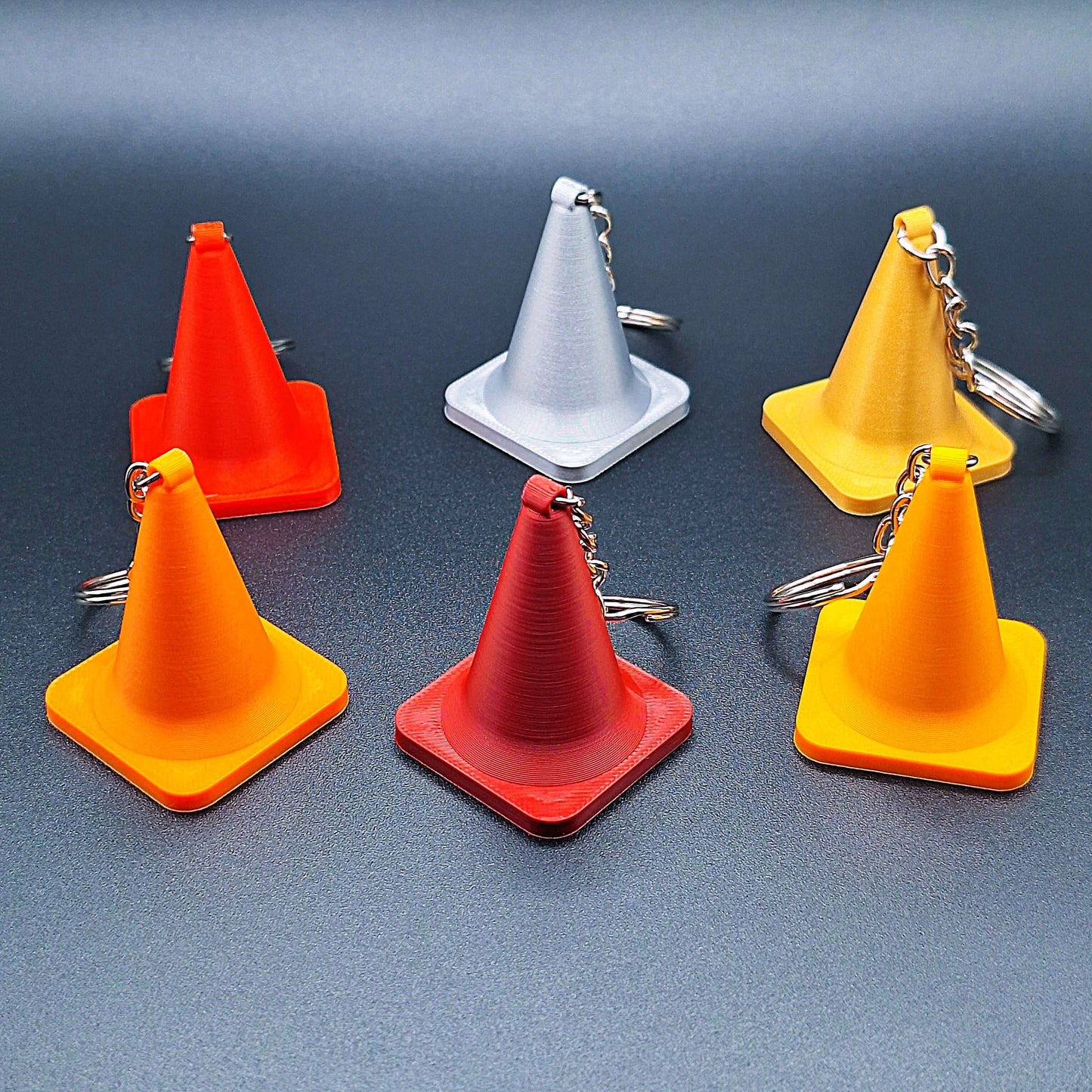 Set of six traffic cone keychains in various colors, handmade from biodegradable PLA plastic, perfect for engineers, drivers, or novelty gifts.