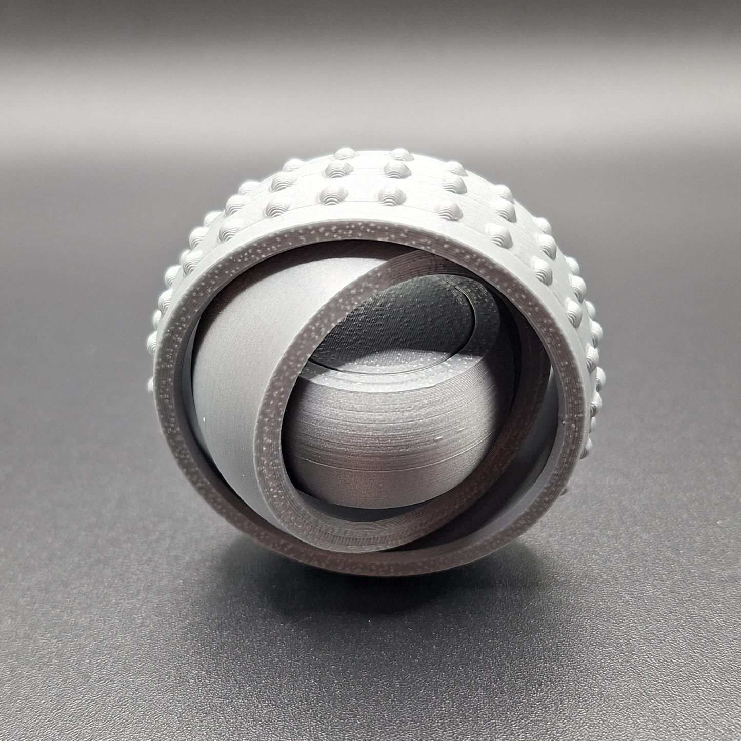 Front view of silver pocket-sized fidget spinner, minimal and modern design made from plant-based plastic for portable stress relief.