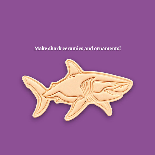 A shark-shaped ceramic or clay mold and template shown on a solid purple background, with the text 'Make shark ceramics and ornaments!' above it.