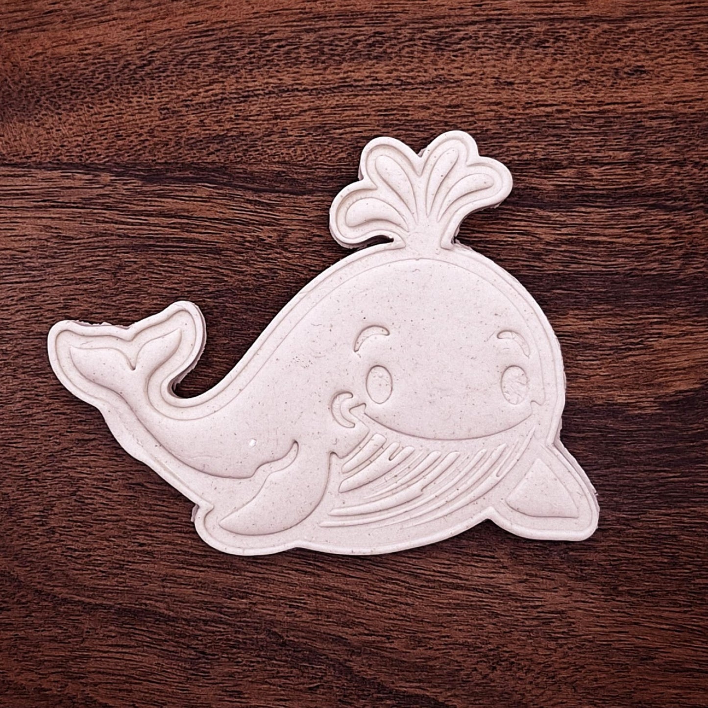 Stamped whale-shaped cookie dough cutout showing detailed fins, tail, and facial features—great for themed baking and decorating.