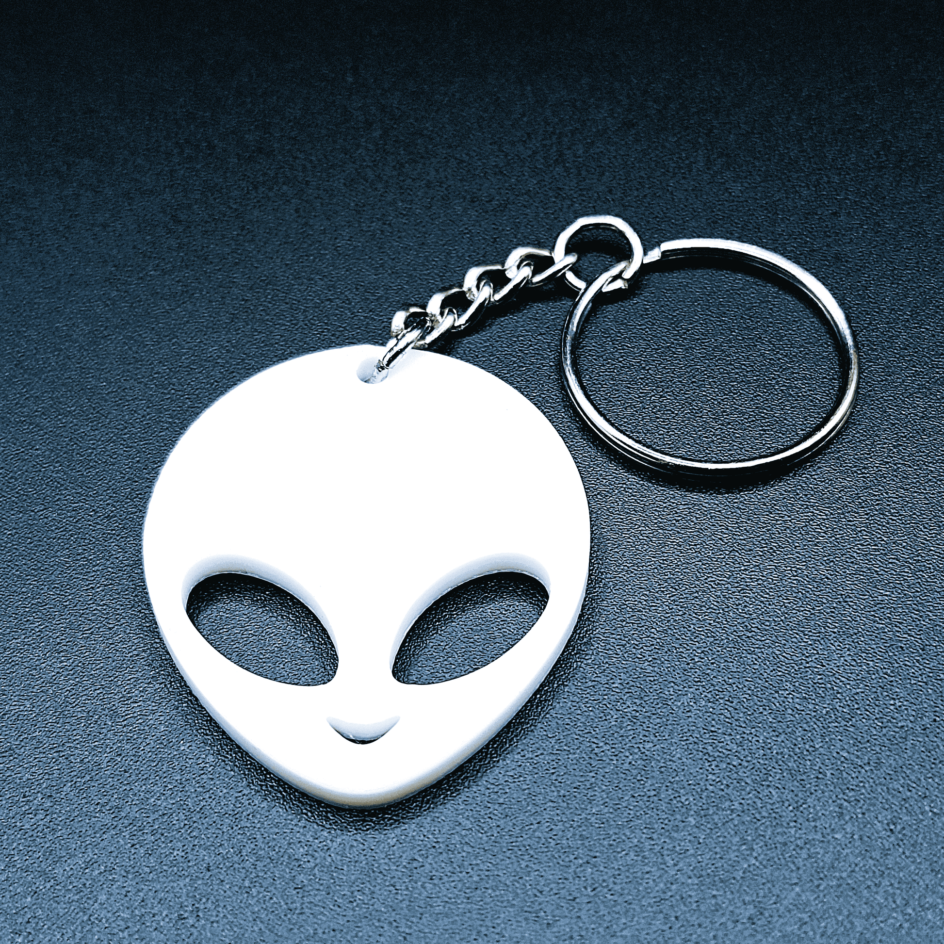 Cute alien keychain with classic UFO-style head and big eyes, front-facing, shown in vibrant white color with keyring.