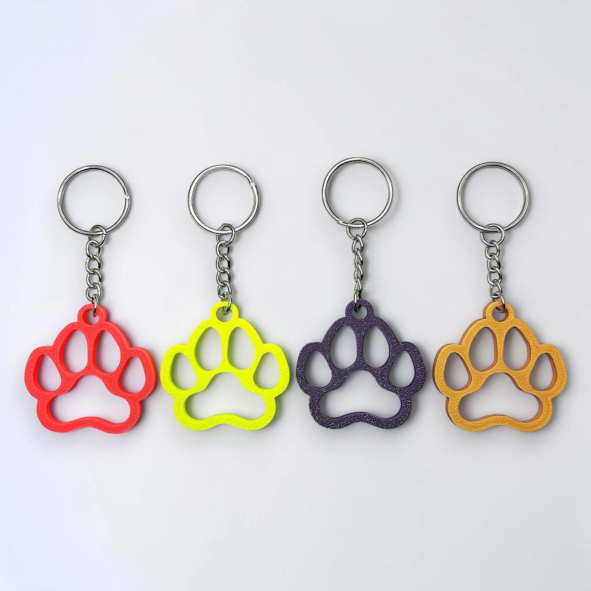 Handmade and customizable paw keychains in four colors, ideal for honoring pets, gifting to animal lovers, or everyday use.