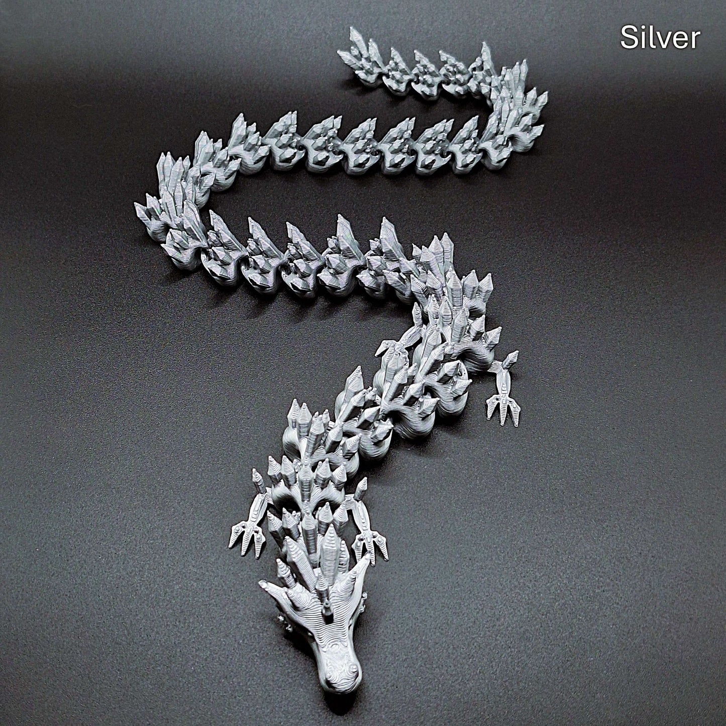 Silver articulated dragon fidget toy with fluid joints and sleek finish, made from plant-based PLA