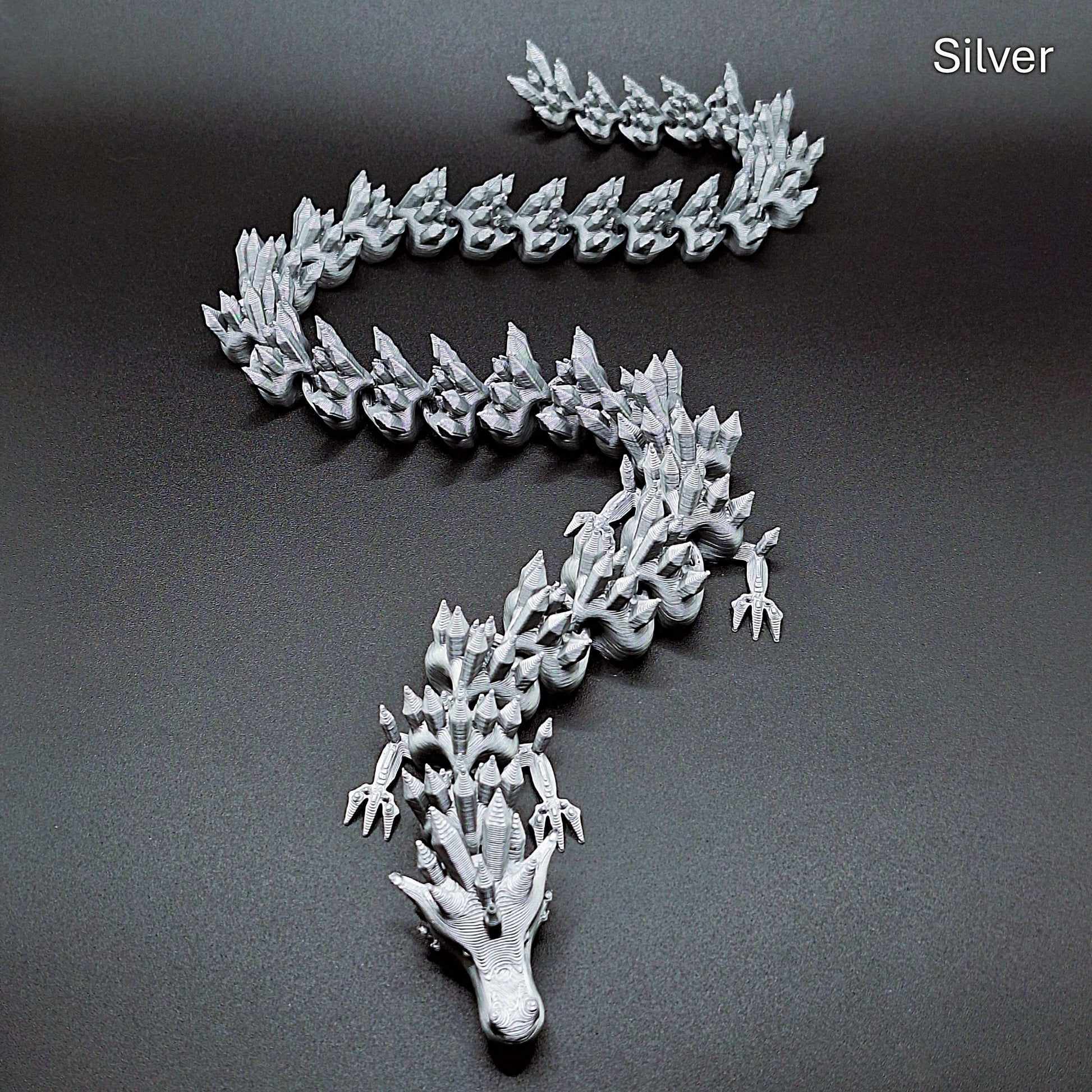 Silver articulated dragon fidget toy with fluid joints and sleek finish, made from plant-based PLA