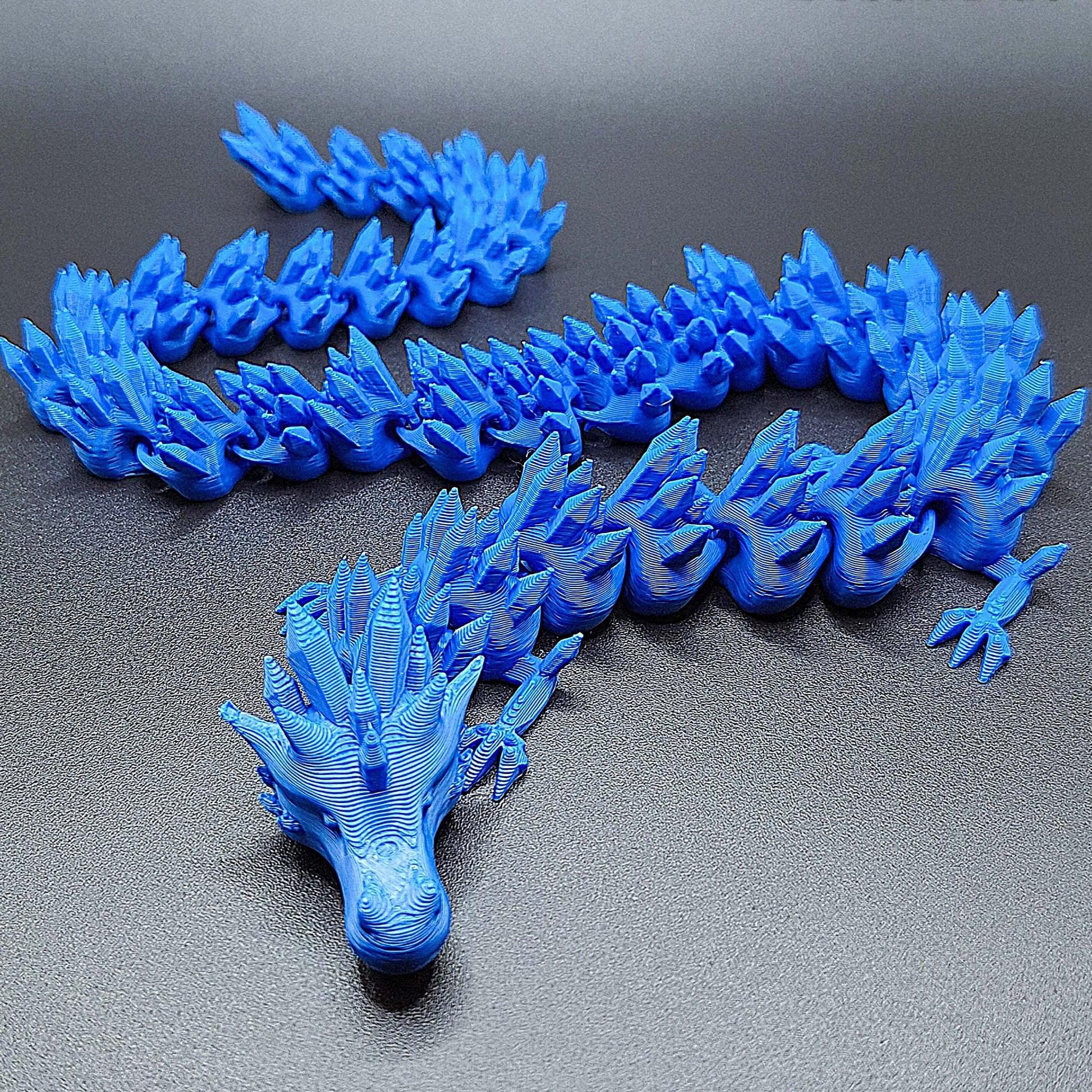 Cobalt blue articulated dragon fidget toy with segmented poseable body, handmade in eco-friendly PLA