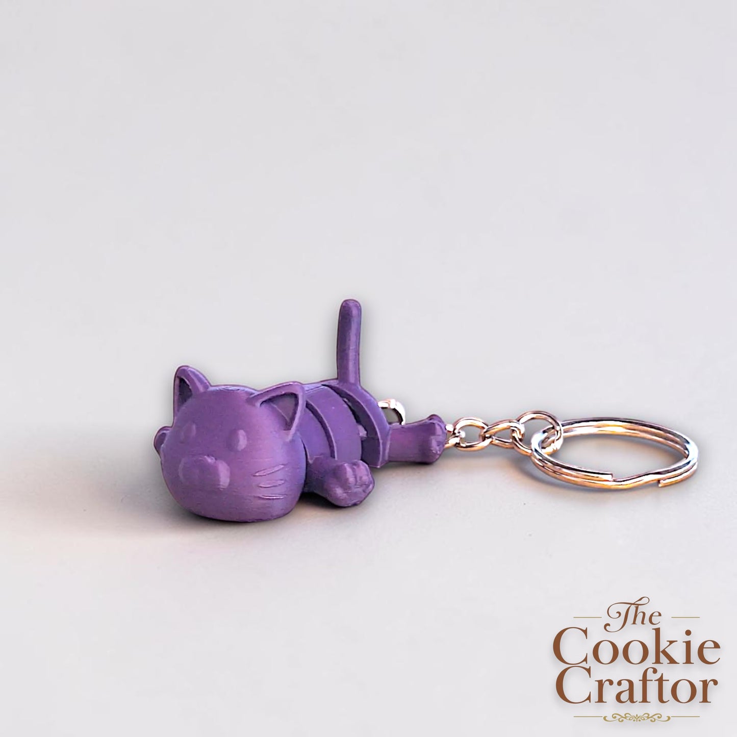 Handmade and customizable articulated cat keychain in indigo purple, great for keys, backpacks, and small gifts with charm.