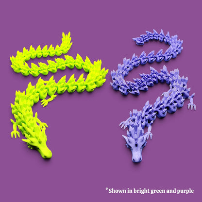 Two articulated dragon fidgets on a solid purple background, one in bright lime green and the other in lavender purple, with a text note at the bottom indicating alternate colors.