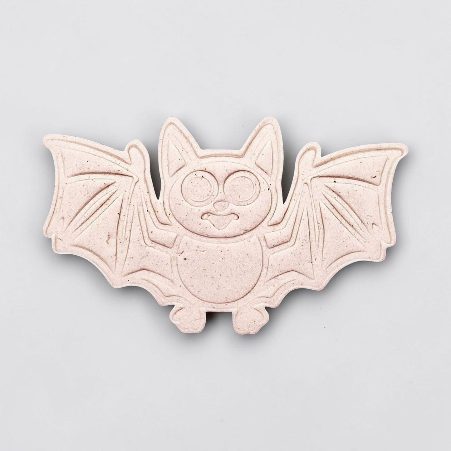 Dough cutout with bat design pressed by cutter and stamp set, showing detailed lines—great for easy Halloween cookie decorating without icing.