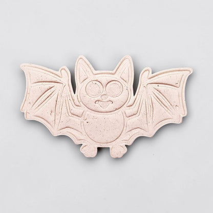 Dough cutout with bat design pressed by cutter and stamp set, showing detailed lines—great for easy Halloween cookie decorating without icing.