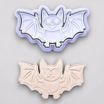 Bat cookie cutter with matching stamp and dough cutout with bat design pressed by cutter and stamp set, showing detailed lines—great for easy Halloween cookie decorating without icing.