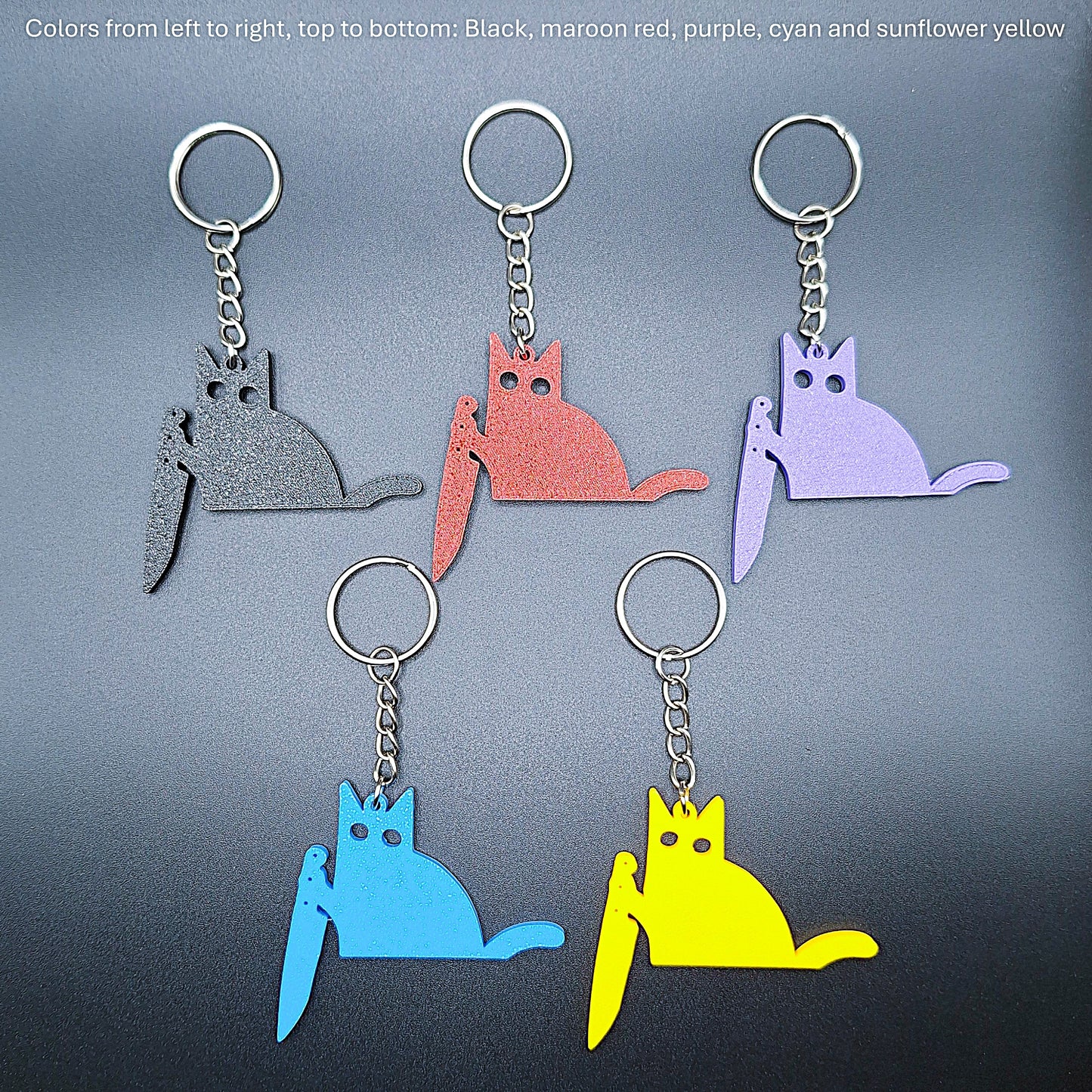 Five colorful black cat knife keychains lined up side by side, each holding a knife, handmade and perfect for unique party favors or spooky gifts.