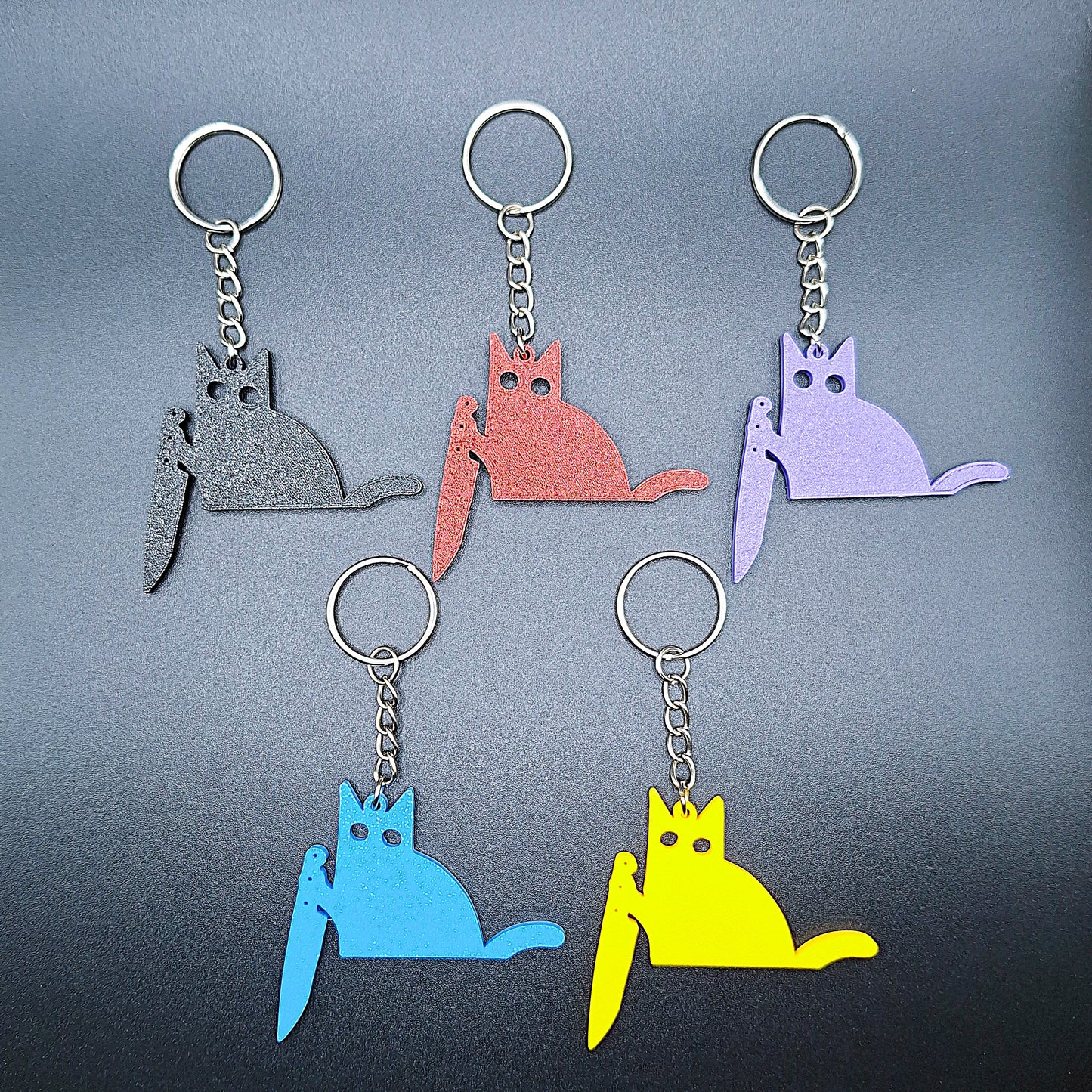 Close-up of five black cat knife keychains in assorted colors, showcasing detail and custom color options for creepy cute key rings.