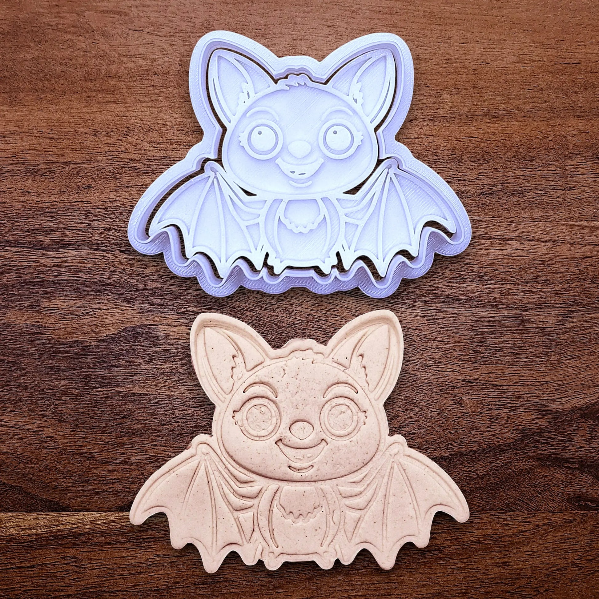 Cute bat cookie cutter with stamp alongside a dough cutout and imprint - adds cute Halloween charm, complete with cute details for whimsical baking, parties, or spooky gifting. Handmade and customizable in 30 colors.