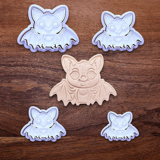 Multiple cute bat cookie cutters with stamps alongside a dough cutout and imprint - adds cute Halloween charm. Complete with cute details for whimsical baking, parties, or spooky gifting. Handmade and customizable in 30 colors.