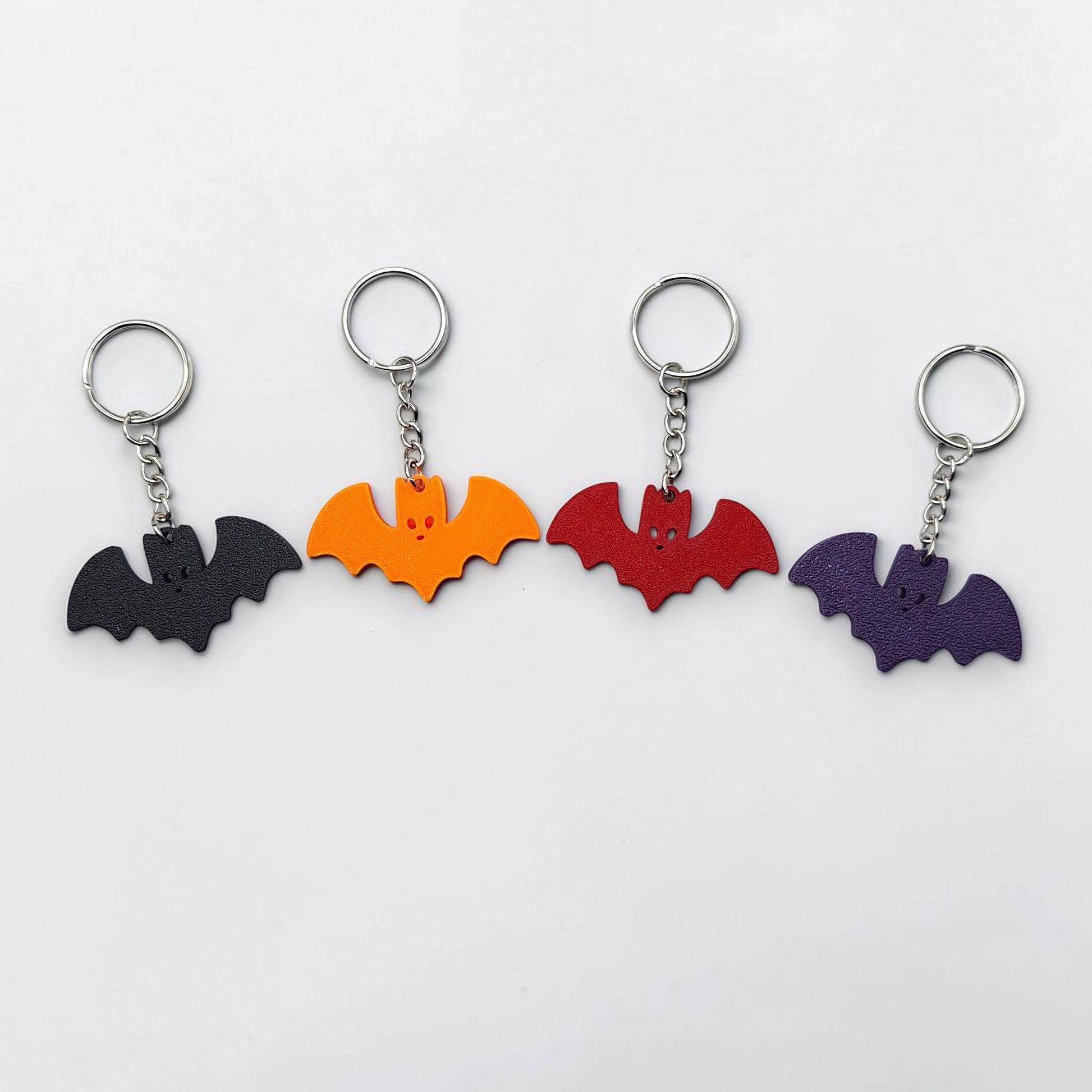 Handmade and customizable bat keychains in various colors, perfect for Halloween gifts, party favors, or gothic-themed keyring collections.