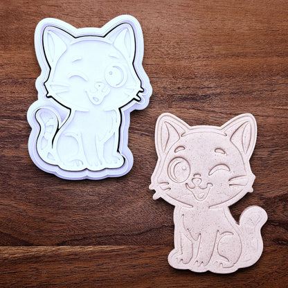 Winking cat cookie cutter and stamp alongside a dough cutout and imprint, great for creating detailed, cat-themed cookies, fondant pieces, or party treats for birthdays, parties and craft projects.