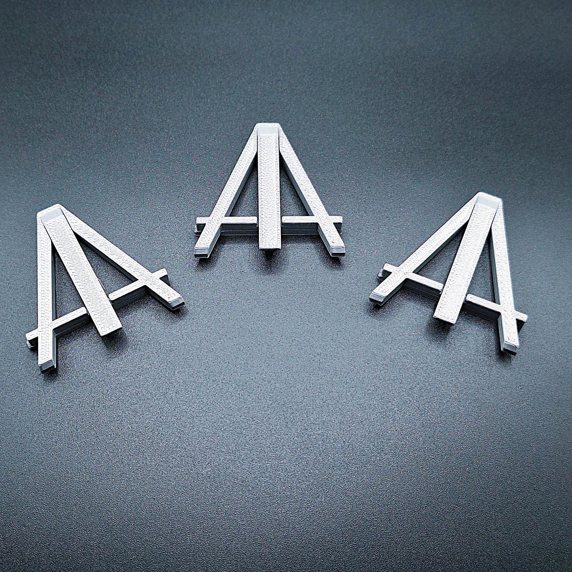 Mini foldable easels in silver – sleek and portable display stands ideal for showcasing coins, trading cards, artwork, signs, photos, or merchandise at craft fairs, shops, and events.