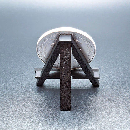 Reverse side of mini foldable easel, shown holding an American Silver Eagle, showcasing the foldable arm and sturdy design.