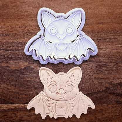 Cute bat cookie cutter with stamp alongside a dough cutout and imprint - adds cute Halloween charm, complete with cute details for whimsical baking, parties, or spooky gifting. Handmade and customizable in 30 colors.