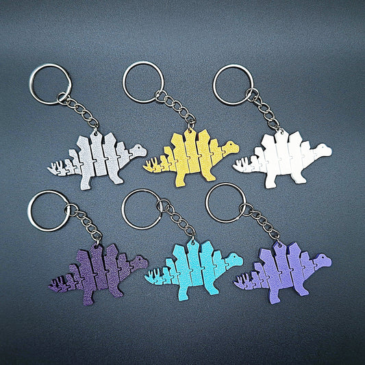 Top view of six fidget dinosaur keychains with articulated segments, ideal for sensory use, kids’ gifts, or dino-themed party favors.