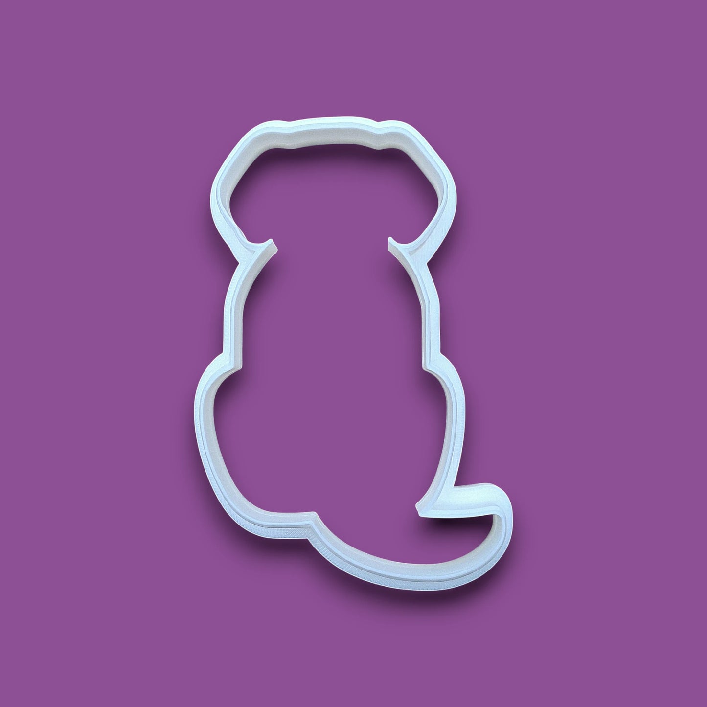 A plastic dog-shaped cookie cutter, shown on a solid background.