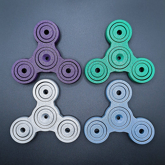 Colorful 3" pronged fidget gyro spinners in four colors—perfect stress relief tool for focus, anxiety, and sensory play. Eco-friendly, handmade.