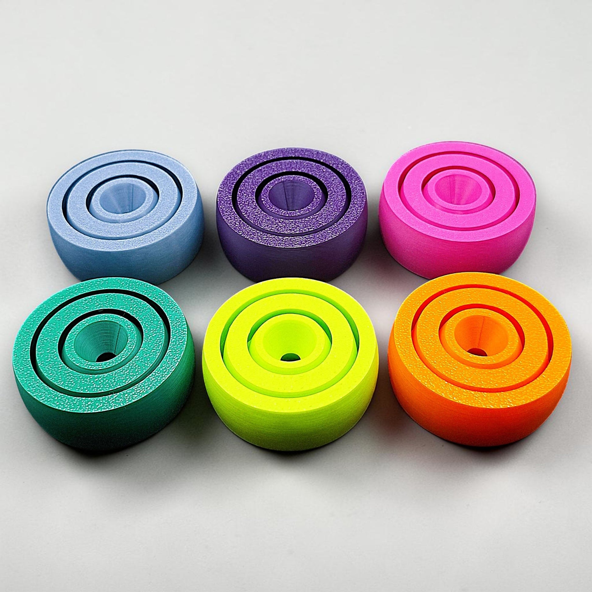 View of six smooth-surfaced fidget spinners in assorted colors, great for tactile calming, fidgeting, and mental focus.