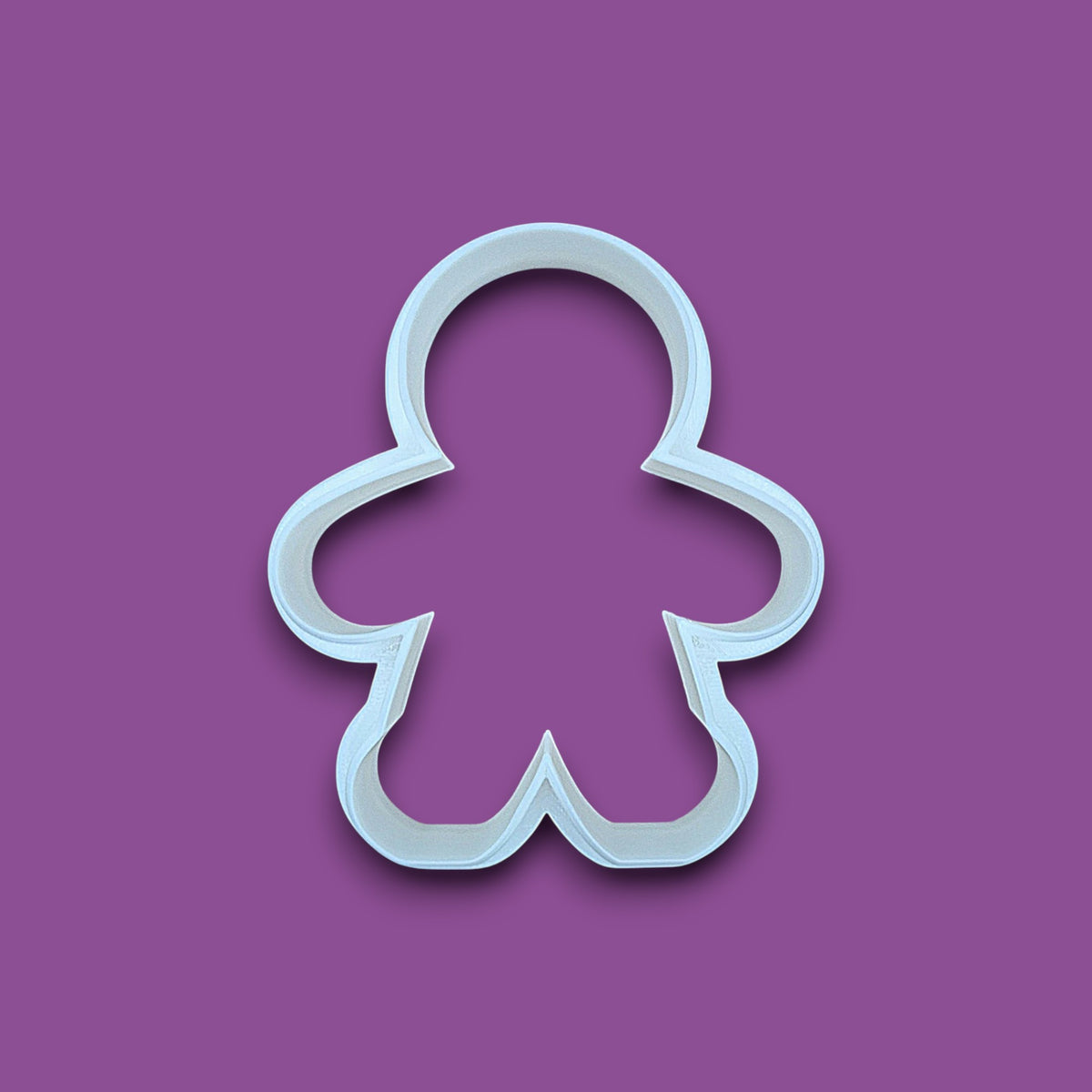 A white plastic gingerbread man cookie cutter shown on a solid purple background.