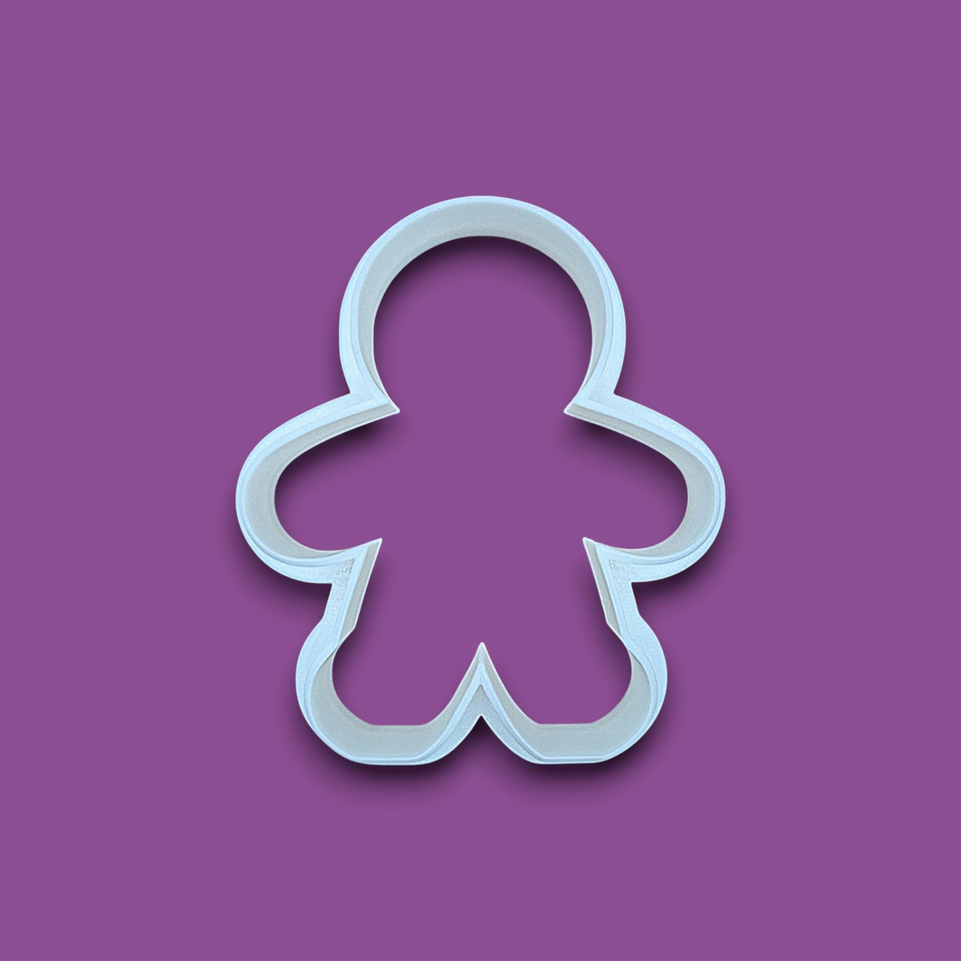 A white plastic gingerbread man cookie cutter shown on a solid purple background.