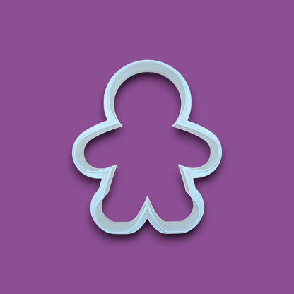 A white plastic gingerbread man cookie cutter shown on a solid purple background.