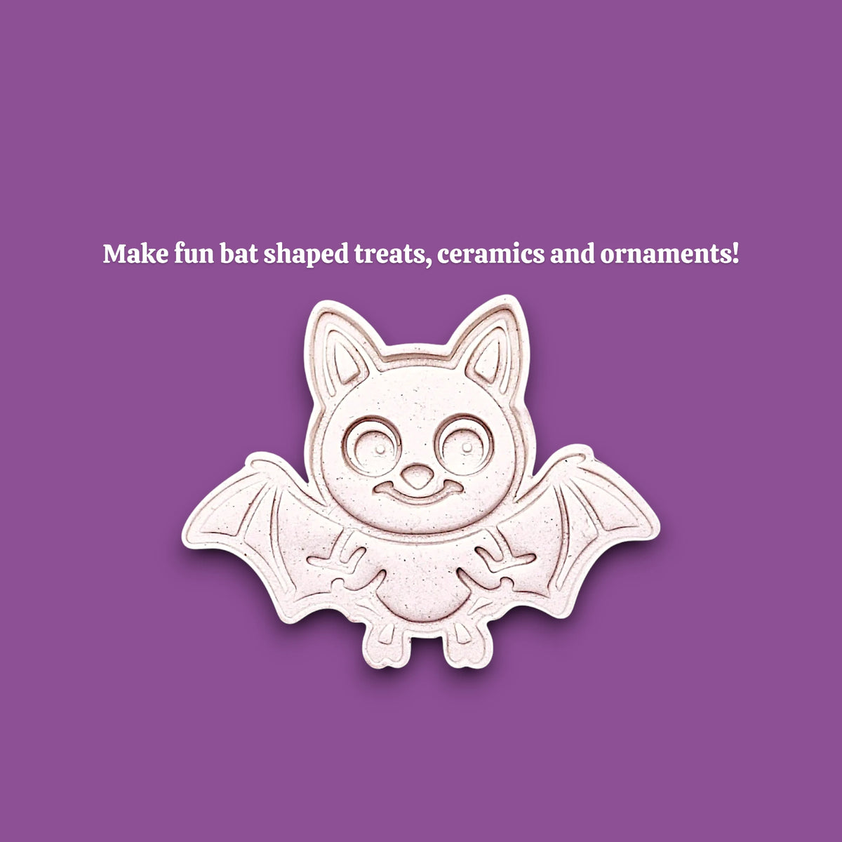 A cute bat-shaped cookie cutter mold shown on a solid purple background with white text that reads 'Make fun bat shaped treats, ceramics and ornaments!'. The bat is off-white with a light pinkish-beige undertone and a subtle drop shadow.