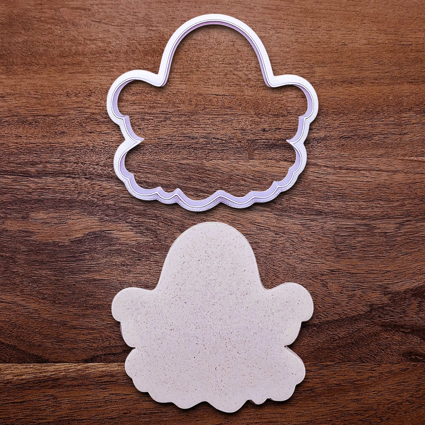 Handmade and customizable ghost cookie cutter alongside a dough cutout and imprint, great for baking Halloween trick or treats or kid-friendly spooky snacks.
