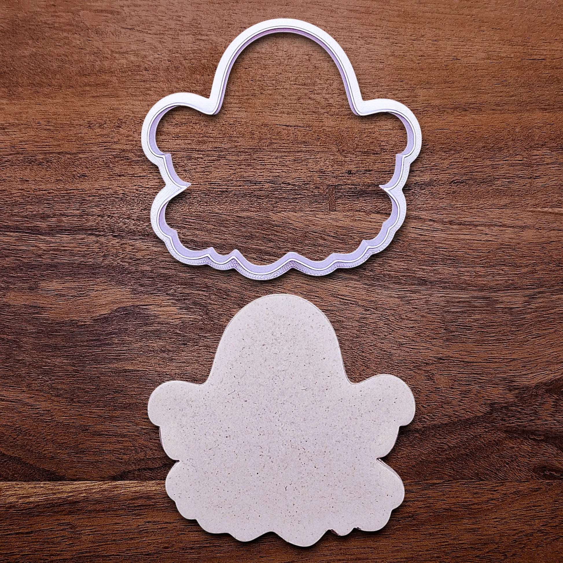 Handmade and customizable ghost cookie cutter alongside a dough cutout and imprint, great for baking Halloween trick or treats or kid-friendly spooky snacks.