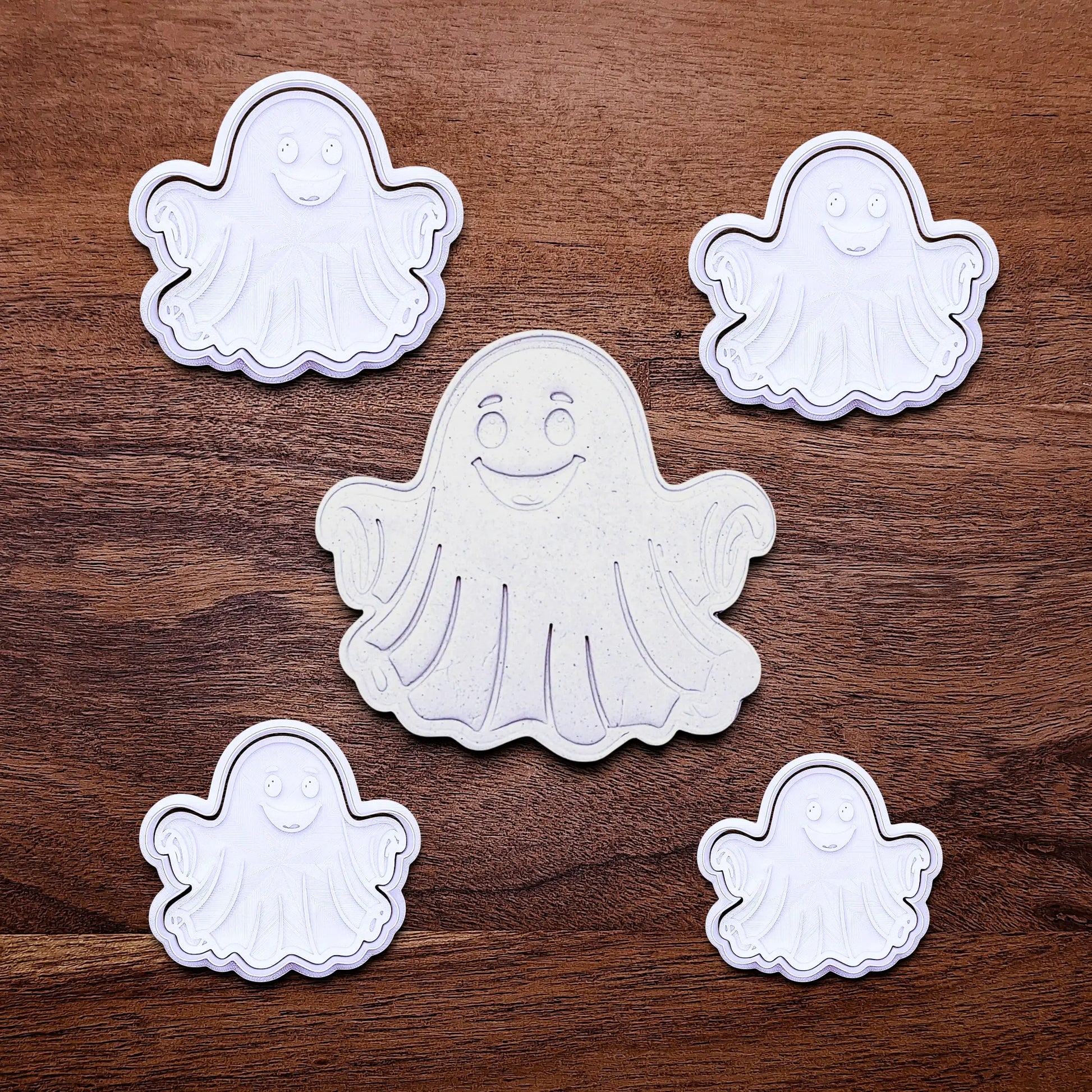 Handmade and customizable ghost cookie cutters and stamps alongside a dough cutout and imprint, great for baking Halloween trick or treats or kid-friendly spooky snacks.