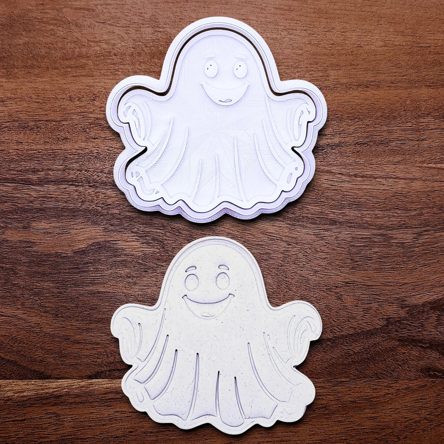 Handmade and customizable ghost cookie cutter and stamp alongside a dough cutout and imprint, great for baking Halloween trick or treats or kid-friendly spooky snacks.