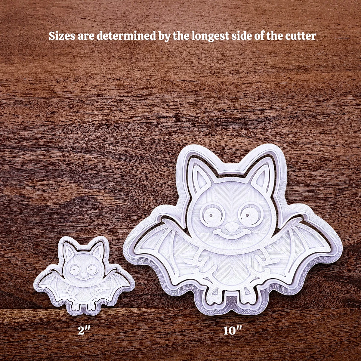 Two bat-shaped cookie cutters with sizes indicated on a light gray background, showing how size increases work.
