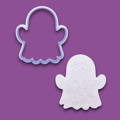 A ghost-shaped cookie cutter outline shown above a matching cutout sample on a solid purple background.