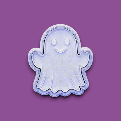 A ghost-shaped cookie cutter or stamp with a smiling face, shown on a solid purple background.
