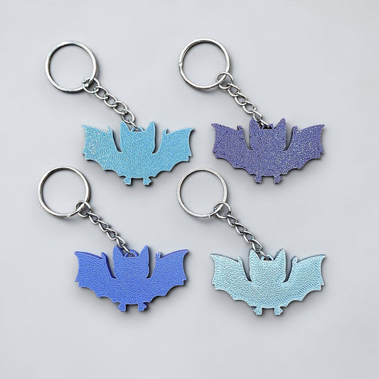 Handmade and customizable bat keychains in various colors, perfect for Halloween trick or treats, gothic party favors, and bat-themed accessories. 