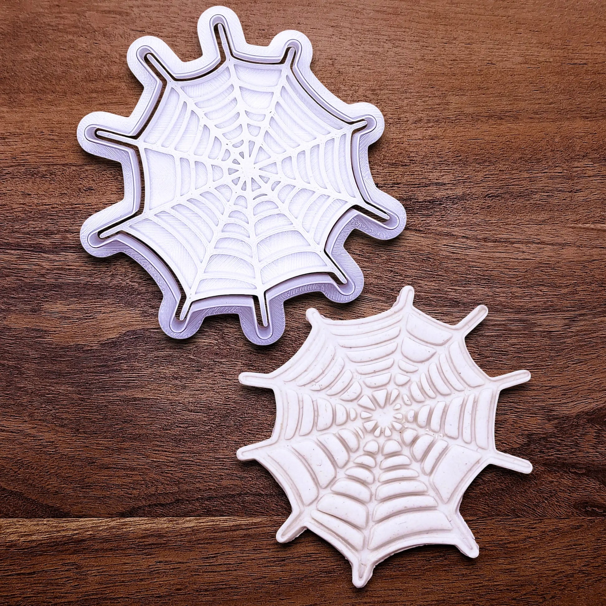 Handmade and customizable Halloween spiderweb cookie cutter and stamp alongside a spiderweb dough cutout and imprint, perfect for fall parties, events, trick or treats, and gifting.